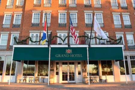 Grand Hotel, brick building with green awning and flags, sunny day.