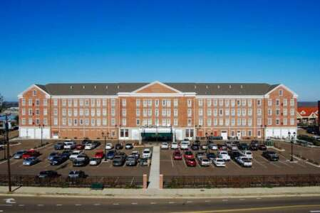 A large brick building with a parking lot, under a clear blue sky.