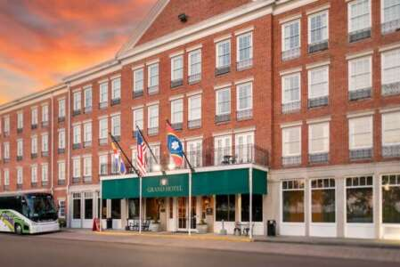 Grand Hotel exterior, red brick building, green awning, flags, bus parked.