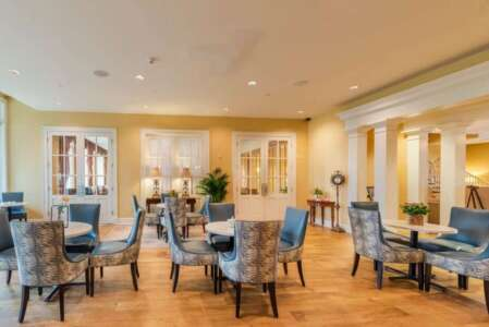 Elegant dining room with blue patterned chairs, round tables, and columns.